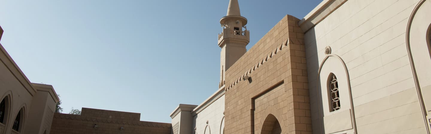A mosque in Riyadh: sand-coloured stone and a white minaret against a clear sky.
